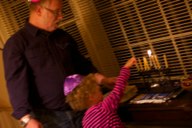 Isis helps grandpa Jeff light the Chanukah candles